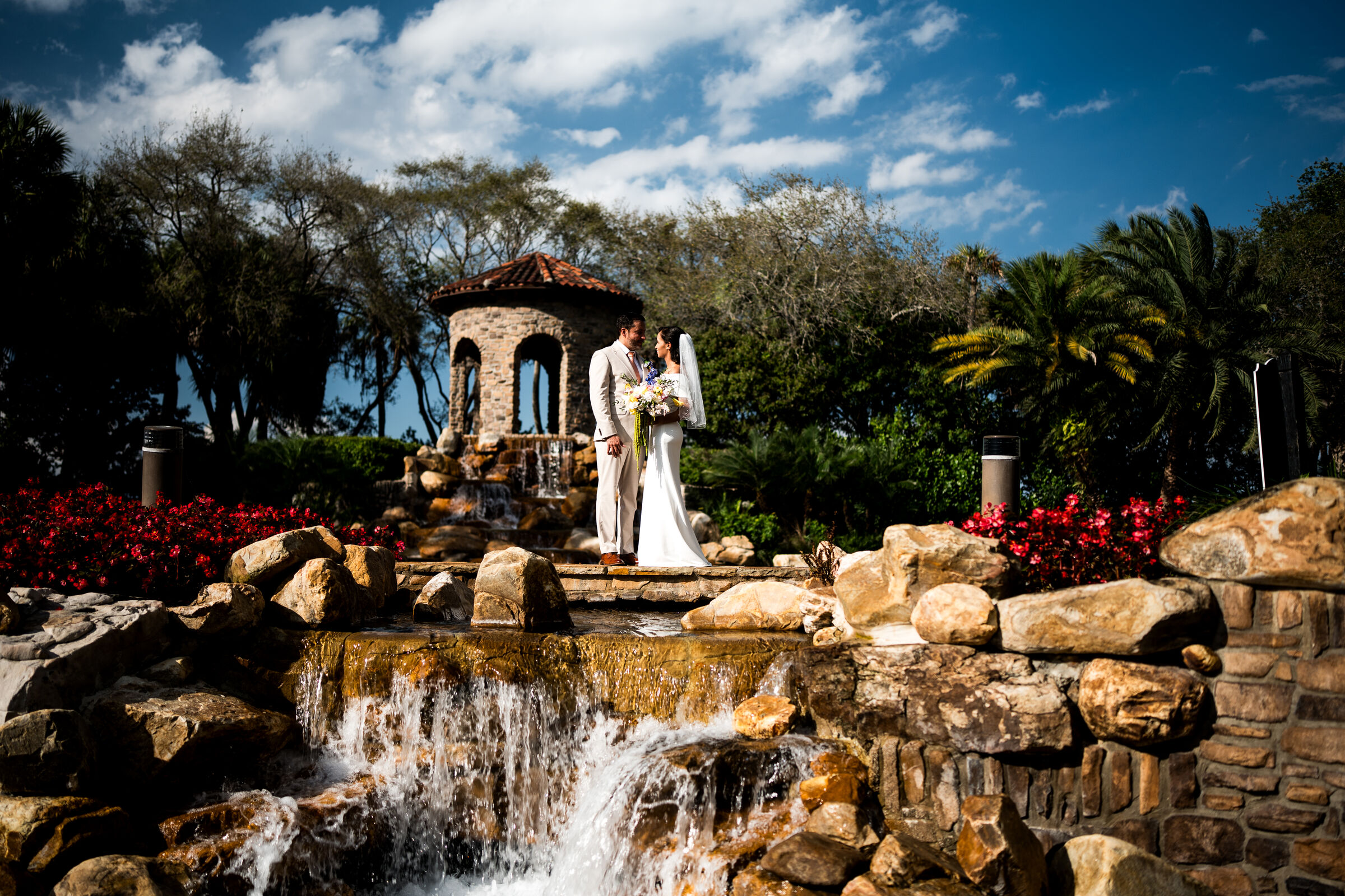 Bride and groom at a garden gazebo above a waterfall