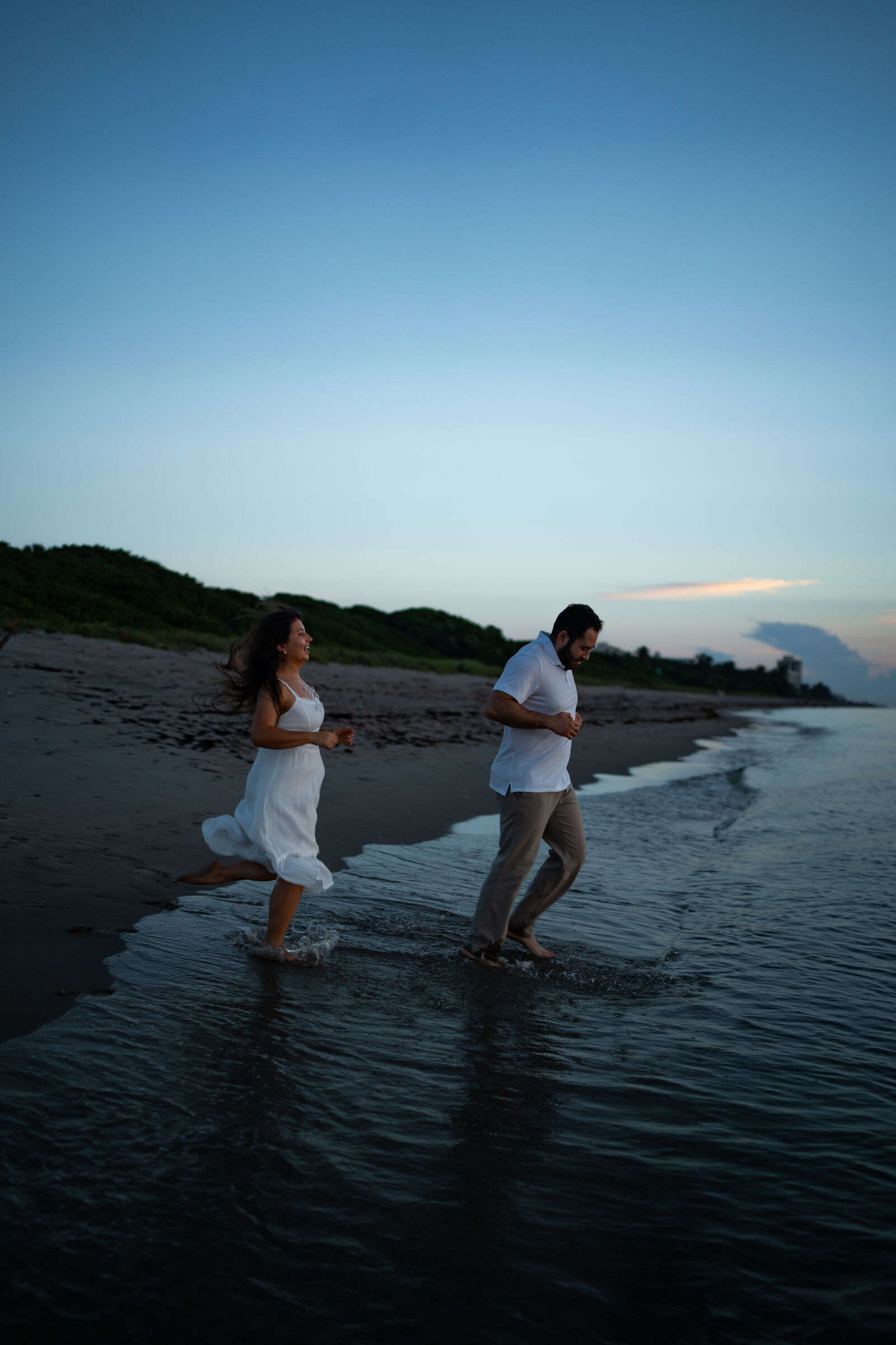 Couple running through the shallows at dusk